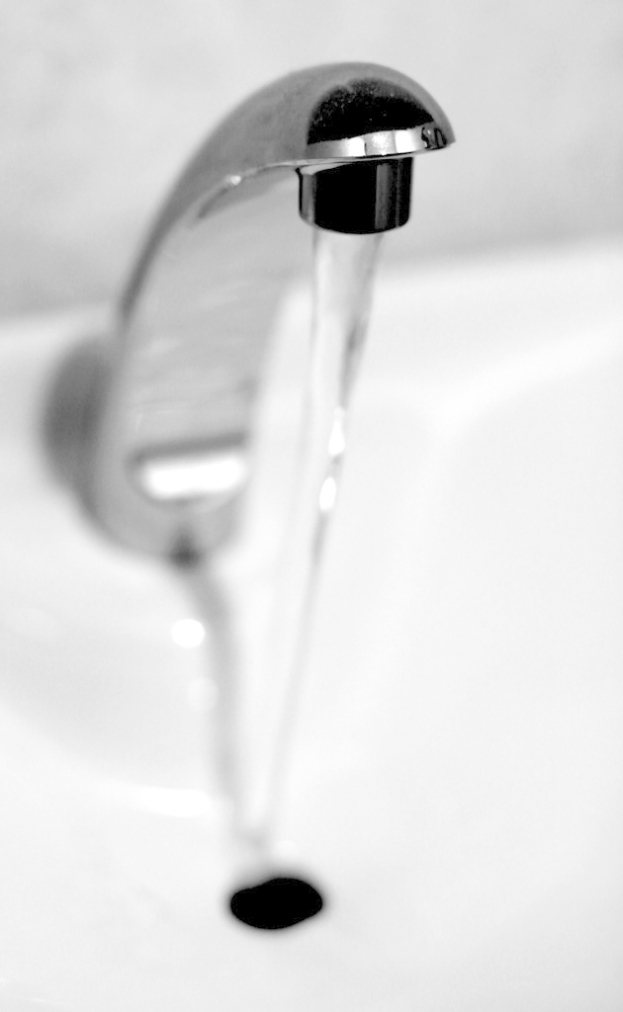 Ein Schwarz-Weiß-Bild eines Wasserhahns mit fließendem Wasser.