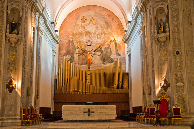 Das Innere einer Kirche mit einer Statue von Jesus Christus in der Mitte und roten St├╝hlen auf der rechten Seite.