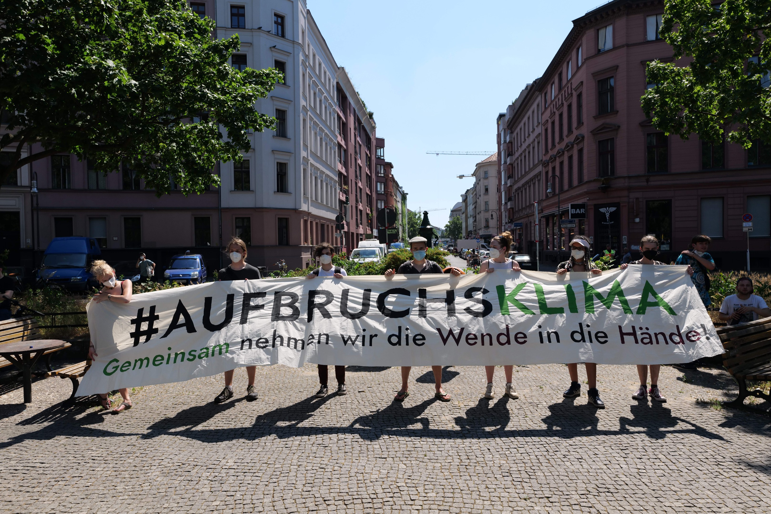 Eine Gruppe von Menschen mit Masken, die ein Transparent mit der Aufschrift 'Aufbruchsklima' tragen, während sie auf einer Klimademonstration in Berlin, Deutschland, protestieren.