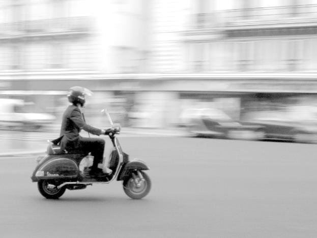 Eine Person auf einem Roller auf einer Straße.
