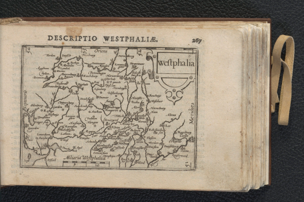 Ein aufgeschlagenes Buch mit einer detaillierten Karte der geografischen Merkmale Westfalens, das auf einer schwarzen Oberfläche liegt.