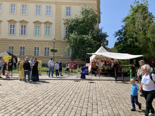Eine Gruppe von Menschen geht eine Kopfsteinpflasterstraße in Krakau, Polen, entlang, mit Zelten, Tischen und einem Gebäude mit sichtbarem Text im Hintergrund.
