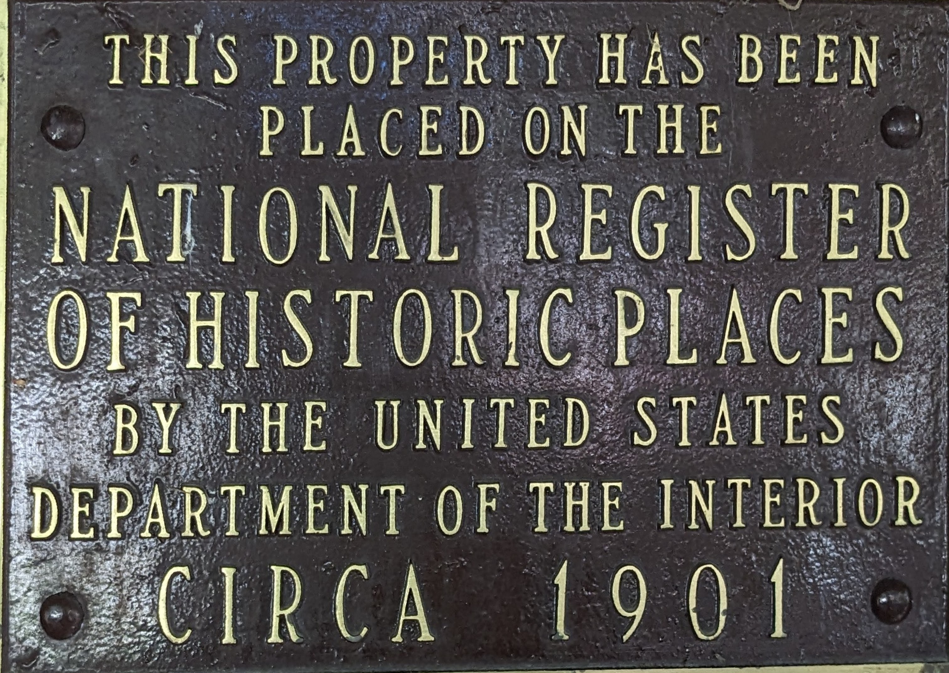 Eine Metalltafel an einem Gebäude mit der Aufschrift "Dieses Gebäude steht unter Denkmalschutz".