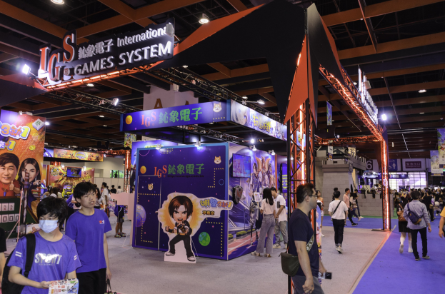 Eine Gruppe von Menschen geht durch einen Messesaal mit Ständen, trägt Taschen und hält Gegenstände, mit vielen anderen im Hintergrund auf einer Gaming-Messe in China.