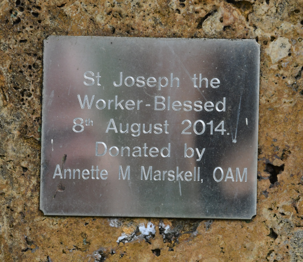 Eine Steinwand mit einer Metalltafel, auf der "St. Joseph der Arbeiter-Gesegnet 8. August 2014" steht.