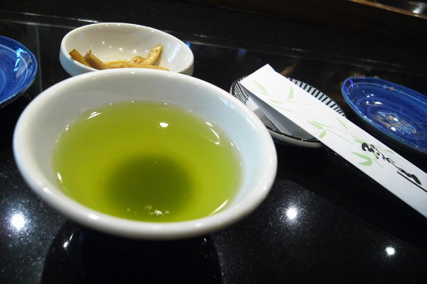 Ein schwarzes Tablett mit einer Suppenschüssel, einem Teller mit Lebensmitteln und einem unbekannten Objekt.