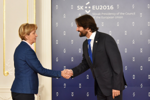 Bundeskanzlerin Angela Merkel und Bundespräsident Joachim Gauck schütteln sich lachend vor einer Wand mit einem "EU-Gipfel"-Plakat und einer Tür die Hände.