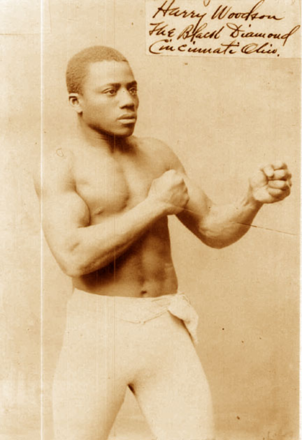 Ein Mann in einem Boxring mit Handschuhen und Shorts, der entschlossen in die Ferne schaut.