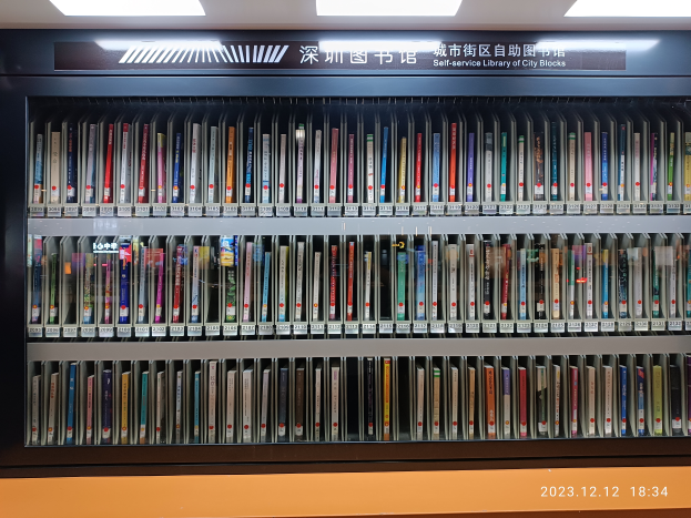 Eine gut beleuchtete Bibliothek mit zahlreichen Büchern auf Regalen, ein Textschild und ein Wasserzeichen unten, das an eine Selbstbedienungsbibliothek von Stadtblöcken erinnert.