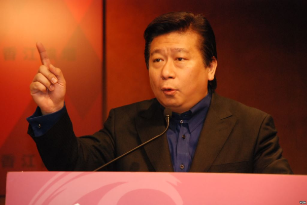 Ein Mann im Anzug und Krawatte hält eine Rede an einem Rednerpult mit einem Mikrofon und sieht ernst aus.