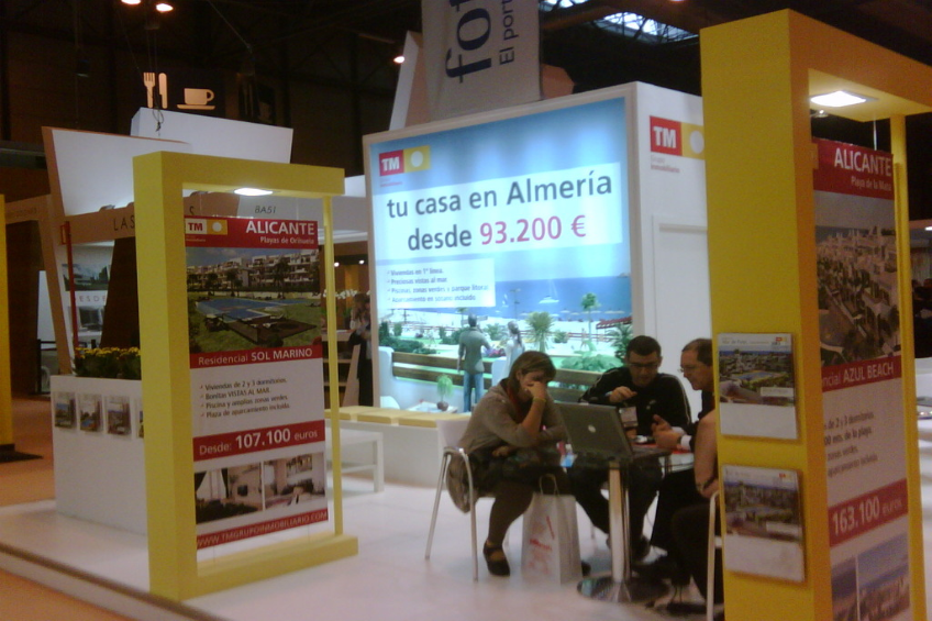 Ein Raum mit Menschen, die an einem Tisch arbeiten, umgeben von mehreren Flyern mit verschiedenen Werbeanzeigen.