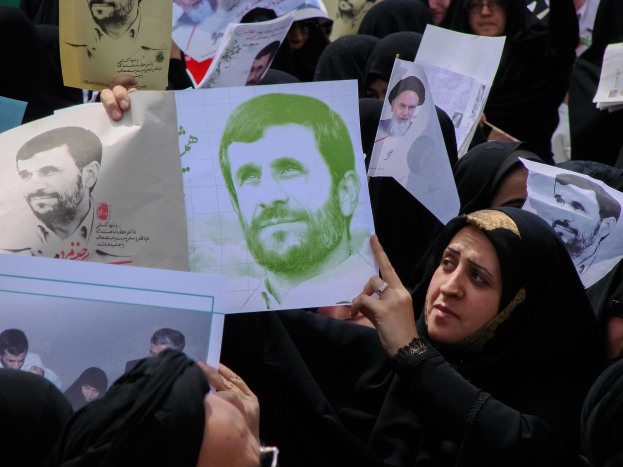 Eine Gruppe iranischer Frauen in schwarzer Kleidung, einige mit Brille, halten Fotos von Präsident Mahmoud Ahmadinejad während einer Kundgebung in Tehran.