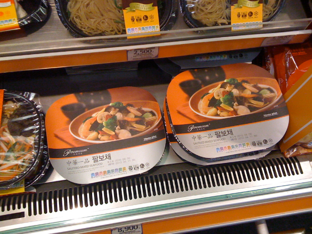 Lebensmittelboxen auf Regalen mit Preisaufklebern.