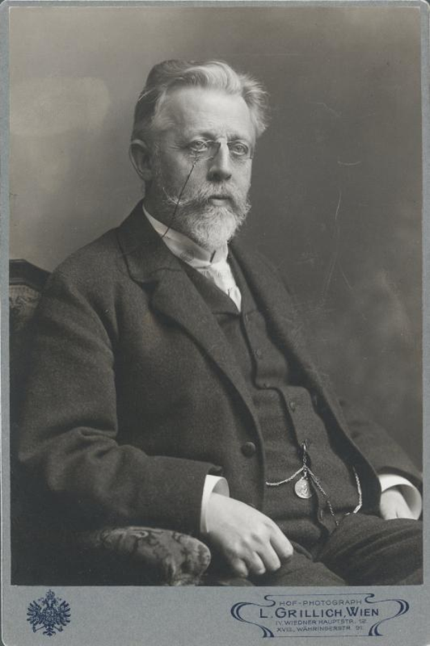 Schwarz-weiß-Porträt eines bärtigen Mannes mit Brille, der in einem Stuhl sitzt, mit Text unten, der ihn als L. Grillich Wien, den Gründer der deutschen Revolution identifiziert.