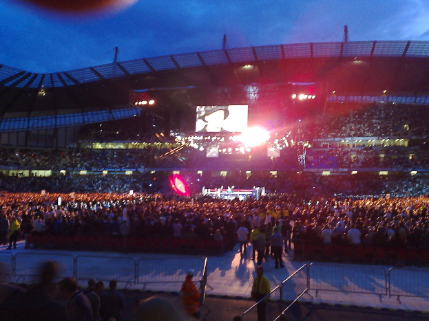 Eine Konzerthalle mit Menschen, Scheinwerfern und einer Projektionsleinwand.