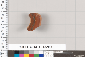 Ein kleines Tonstück wird auf einem Lineal neben einem anderen Lineal platziert, mit einer Skala und Farbkarte unten, die Messungen des Tons zeigen.