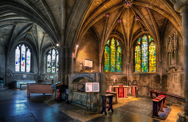 Ein Raum mit Bänken, Tischen, einer Tafel, Fenstern, einer Wand, Kerzen, einem Kamin und Lichtern in der Mitte, digital bearbeitet.