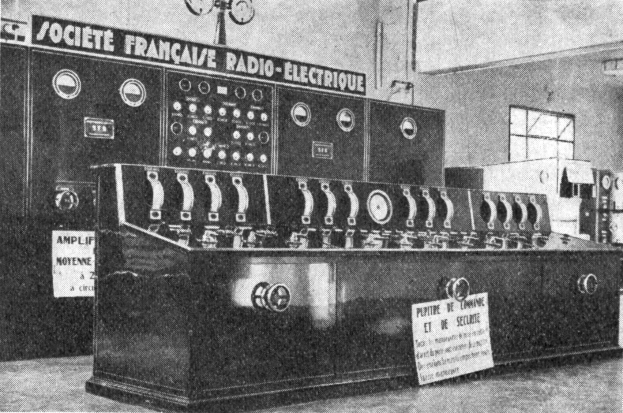 Ein Schwarz-Weiß-Foto eines altmodischen Radios auf einer Oberfläche, mit einem Fenster und anderen Gegenständen im Hintergrund und Text unten, der "Societe Française Radio Electrique" lautet.