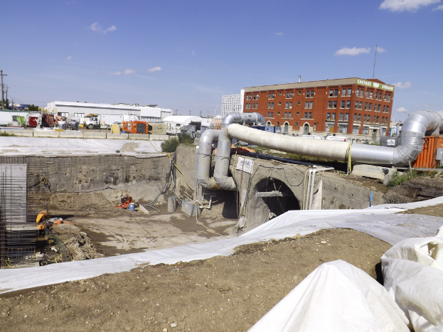 Eine Szene mit Geb├Ąuden, einem Zaun, Fahrzeugen, aktuellen Umfragen, einer Rohrleitung und dem Himmel ├╝berall.