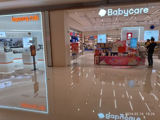 Ein Babyladen in einem Einkaufszentrum mit Menschen, Spielzeugen, Regalen, Schildern, einem Bildschirm und Deckenleuchten, gelegen im Mall of Asia.
