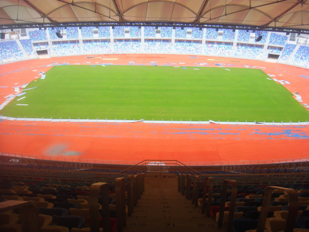 Großes Stadion mit zahlreichen Zuschauern, mit Sitzreihen, Geländern, Treppen und Dach, mit einem sichtbaren Spielfeld in der Mitte.