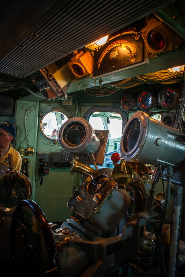 Das Innere eines Zuges mit Sitzen und verschiedenen Gegenständen, eine Person in einem gelben T-Shirt steht links.