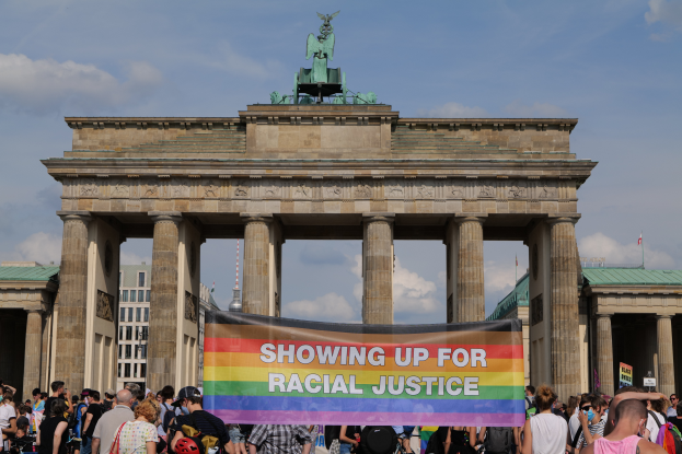Eine Gruppe von Menschen steht vor dem Brandenburger Tor in Berlin, Deutschland, und hält ein Transparent mit der Aufschrift "Rassengerechtigkeit."
