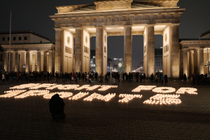 Eine Gruppe von Menschen steht vor dem beleuchteten Reichstagsgebäude in Berlin, Deutschland, mit den Worten "Kämpfe für die Freiheit" auf dem Boden im Vordergrund.