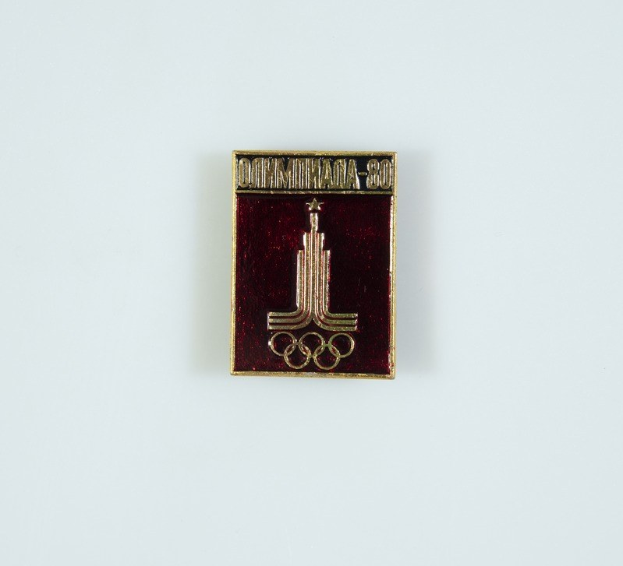 Rote und goldene Emaille-Nadel mit goldenem Rand, die ein modernes weißes Gebäude mit rotem Dach in einem goldenen Rahmen zeigt, zum 80. Jubiläum der Olympischen Spiele in Darmstadt, Deutschland, mit schwarzer Schrift "80. Jubiläum".