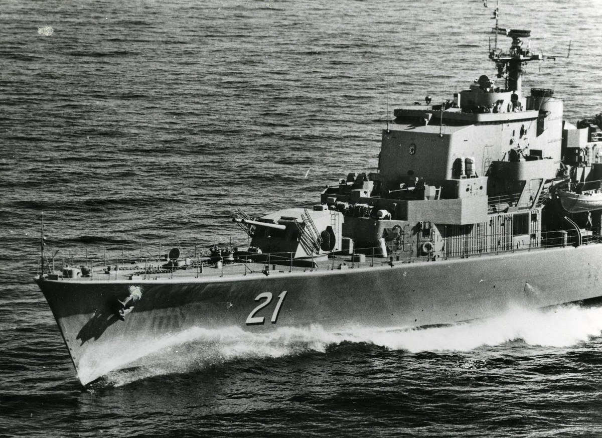 Ein Schwarz-Weiß-Foto eines großen gelenkten Raketenfregatters, das auf dem Wasser fährt und eine sichtbare Identifikationsnummer an seiner Seite trägt.