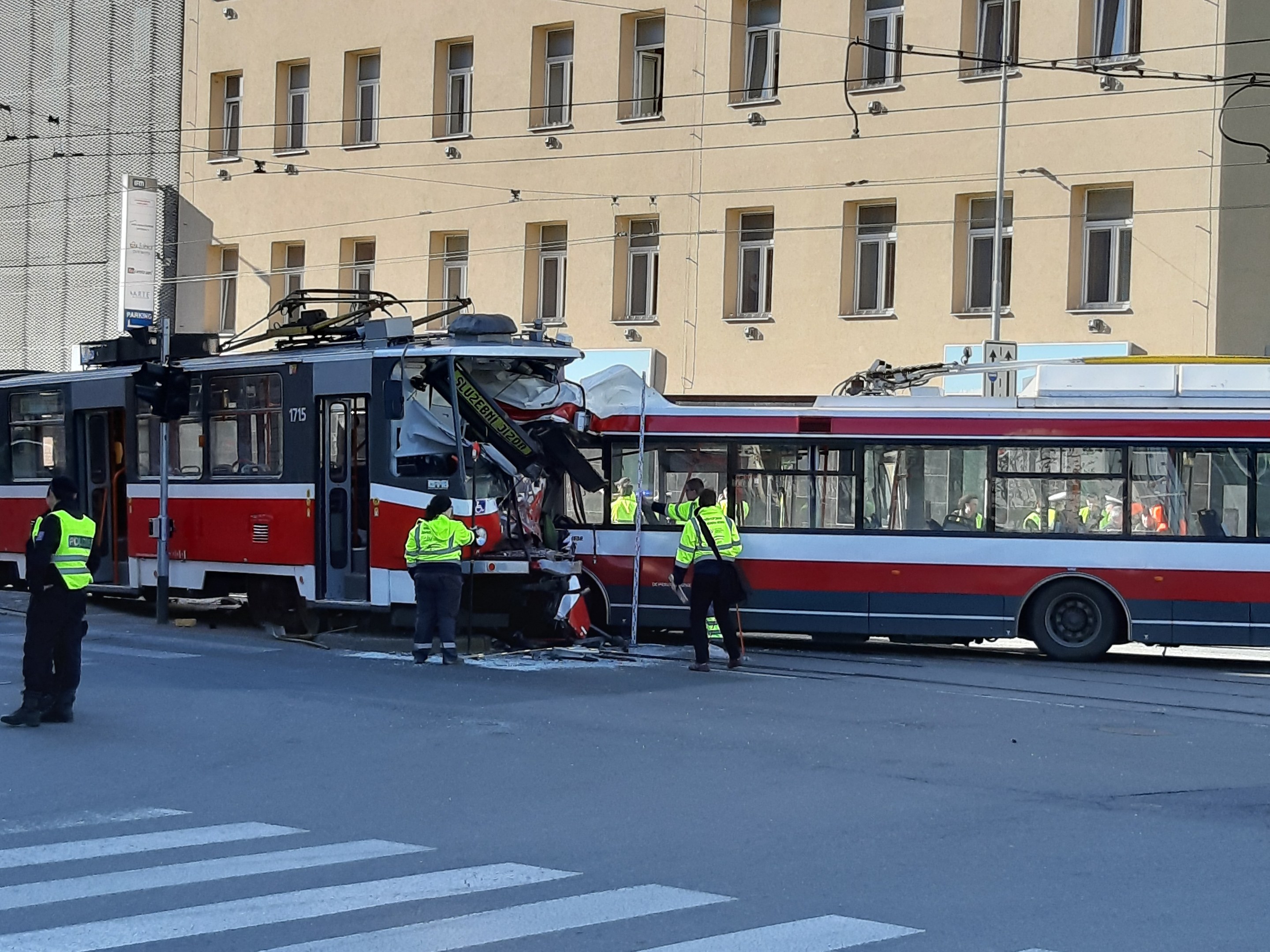 Rote und weiße Tram auf der Straße neben der Straße mit ein paar Menschen in der Nähe und einem Gebäude im Hintergrund.
