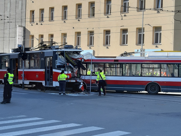 Rote und weiße Tram auf der Straße neben der Straße mit ein paar Menschen in der Nähe und einem Gebäude im Hintergrund.