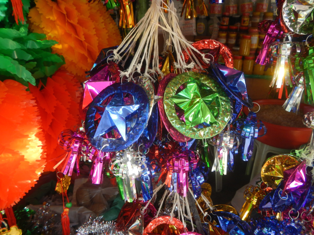 Farbenfrohe Dekorationen, darunter Laternen und Bänder, hängen von der Decke über Regalen voller Flaschen in einer festlichen Atmosphäre.