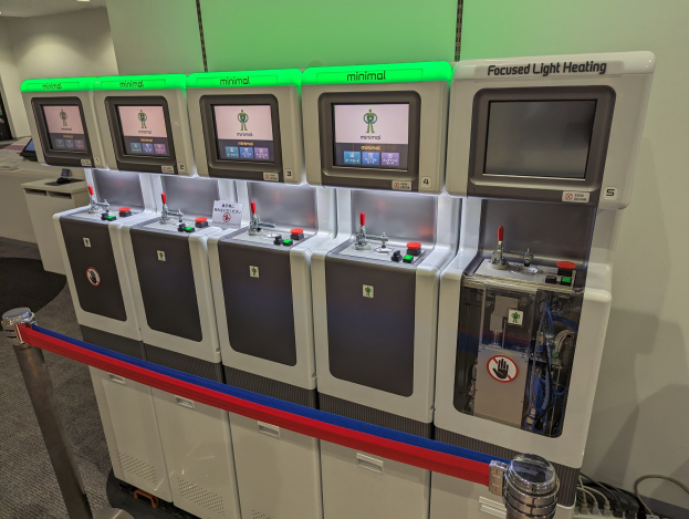 Eine Reihe von Mini-Heizungssystemgeräten mit Steuerknöpfen und -reglern in einem Raum mit einer Wand, Deckenleuchten und einem Boden.