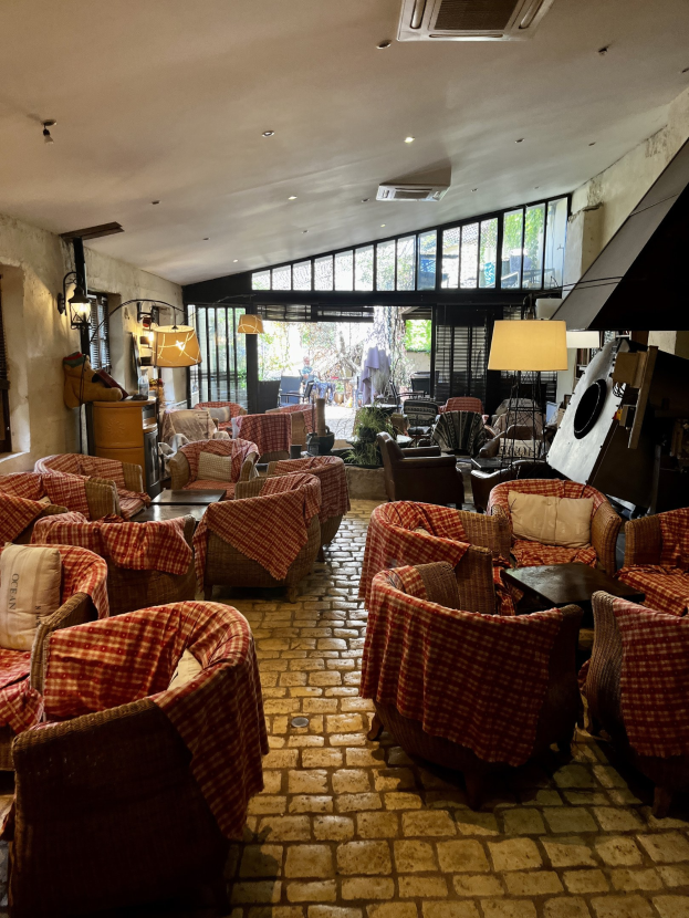 Geräumige Lobby des Hotel de Ville mit zahlreichen Stühlen und Tischen, gepolsterten Sofas, wandmontierten Lampen, einer Deckenklimaanlage und großen Glasfenstern an der Rückseite.