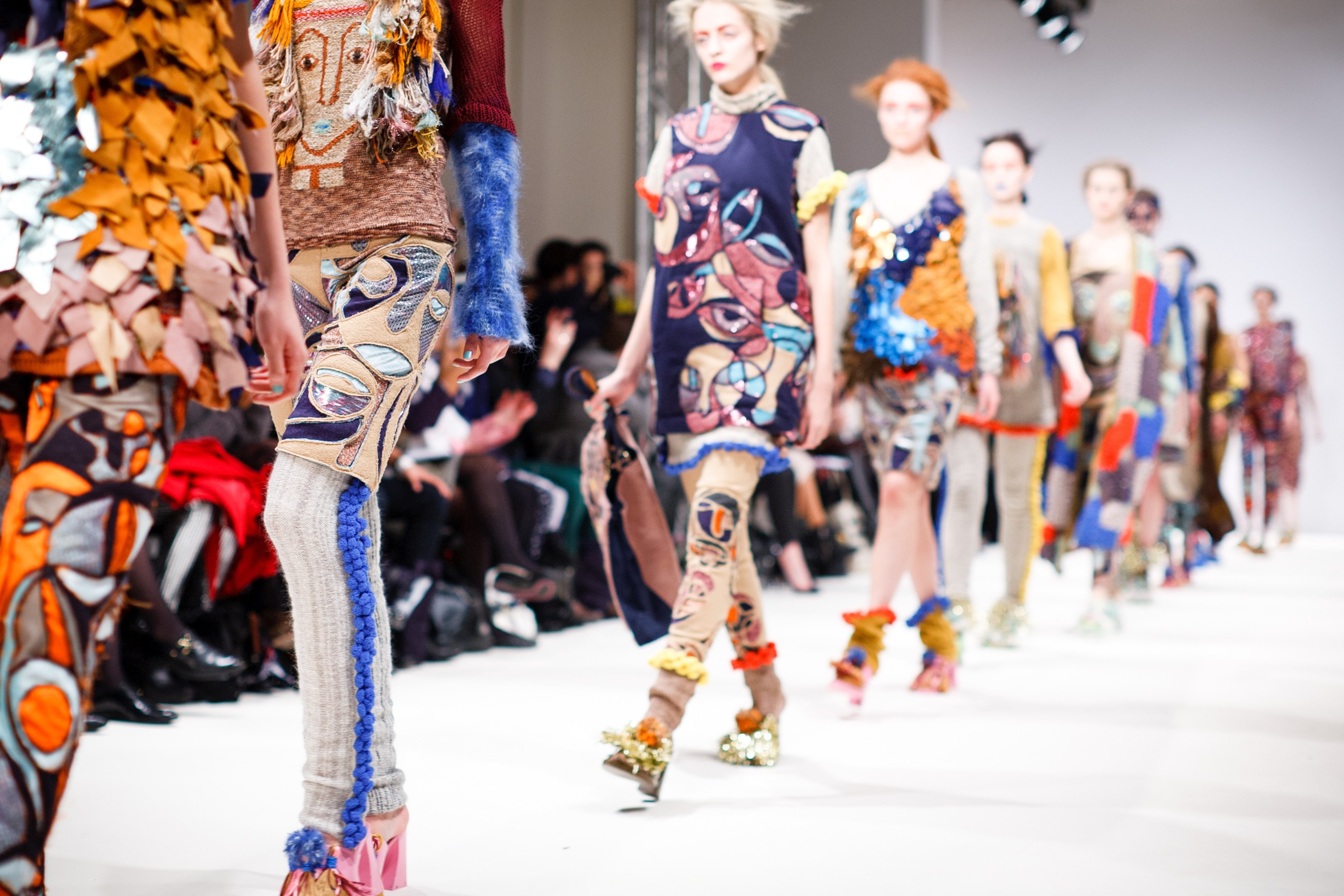 Eine Gruppe Von Frauen Geht Den Laufsteg Bei Der London Fashion Week entlang, Mit Einer Zuschauermenge Im Hintergrund Unter Helllem Licht, Schaffend Ein Traumhaftes Effekt Mit Leichter Hintergrundunschärfe.
