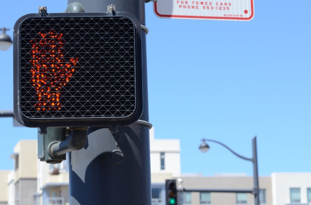 Eine Straßenszene in der Stadt mit Verkehrspfosten, Ampeln, Straßenlaternen, Gebäuden und einem klaren Himmel.