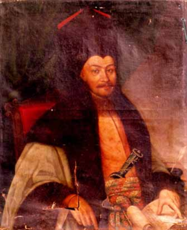 Ein Mann in einem langen Gewand sitzt in einem Stuhl, hält ein Buch und einen Stift, mit einem ernsten und nachdenklichen Gesichtsausdruck, schaut in die Ferne.