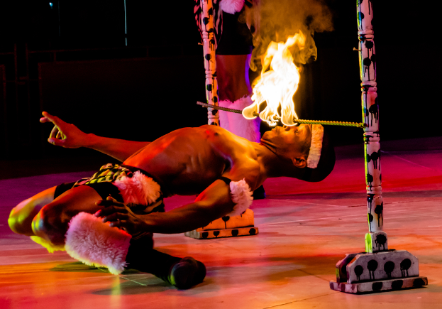 Eine Person schaut auf ein Feuer, das auf einer Stange hängt, die an Pfosten befestigt ist.