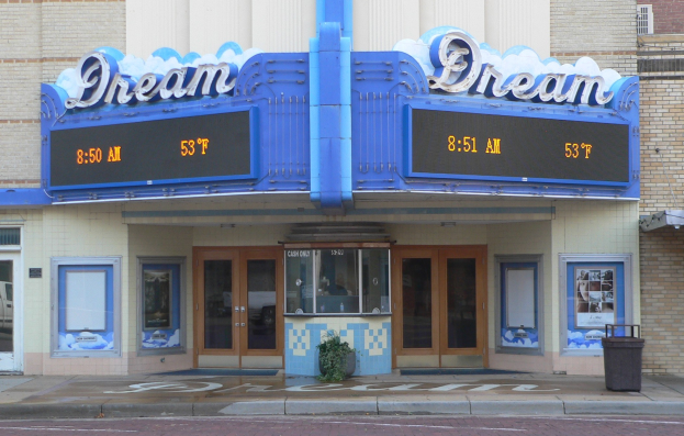 Außenansicht des Dream Theaters in St. Louis, Missouri, mit Glastüren und -fenstern, einem Namensschild, einem Mülleimer, einer Topfpflanze und einer Straße unten.