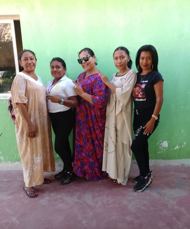 Eine Gruppe von Frauen, die vor einer grünen Wand mit einem Fenster auf der linken Seite steht und an einem Internationalen Frauentag teilnimmt.