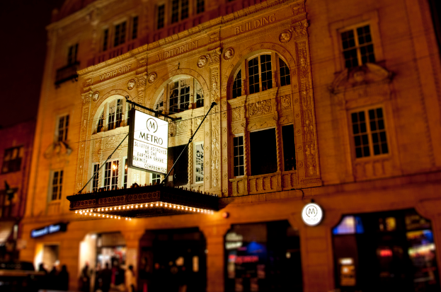 Ein gelbes Gebäude mit Geschäften im Erdgeschoss, eines davon hat eine weiße Tafel mit der Aufschrift "Metro".