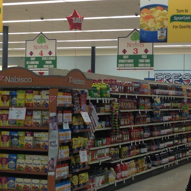Ein Supermarkt-Innenraum mit sichtbaren Lebensmitteln, Deckenbeleuchtung und hängenden Schildern.