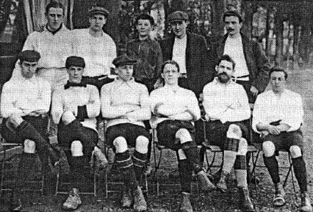 Schwarzes und weißes Mannschaftsfoto des West Bromwich Albion Football Club aus dem Jahr 1918, das sitzende und stehende Männer mit Bäumen im Hintergrund zeigt.